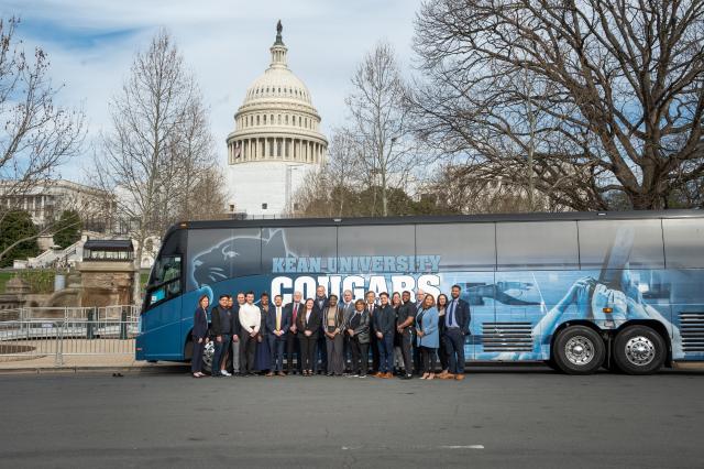Kean University Bus parked in front of the US Capitol Building with students and administrators standing in front of the bus.