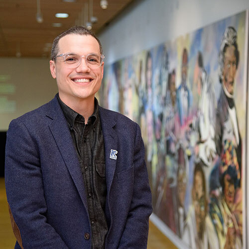 Kean faculty member standing in gallery with large painting in background