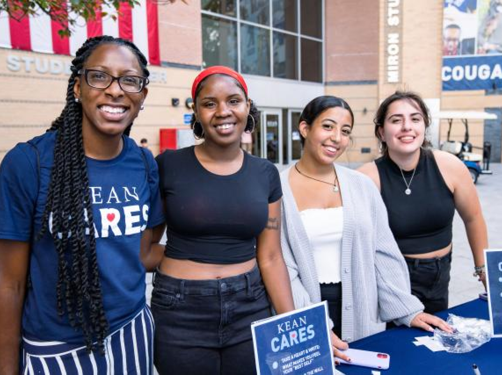 Four students together at a booth for Kean Cares at a volunteer event