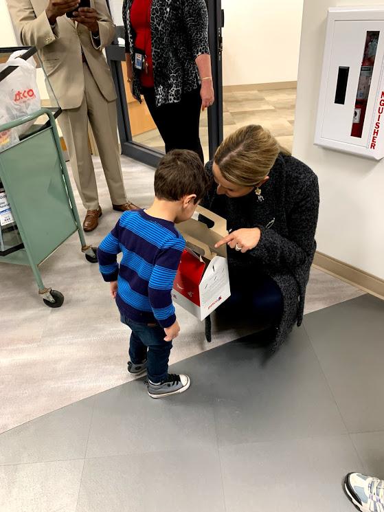 Wolfe bends down to let a boy student look into the hamster box. 