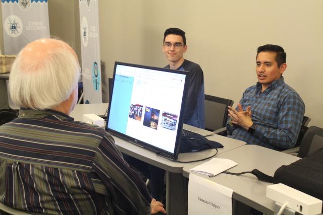 Photo of 2 Computer Science Students - Justin De la Cruz and Jose Salas describing their Capstone project to Prof. Karol