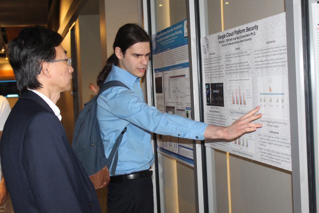 Photo of Computer Science Senior explaining his Google Cloud project (poster) to a professor