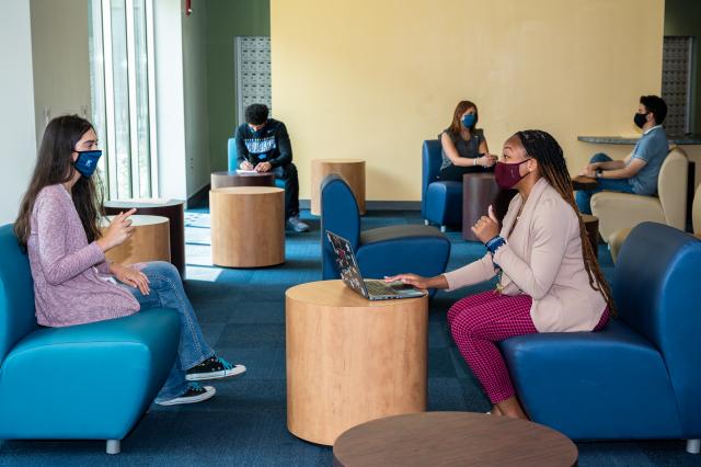 Masked Kean students study and converse in a lounge area
