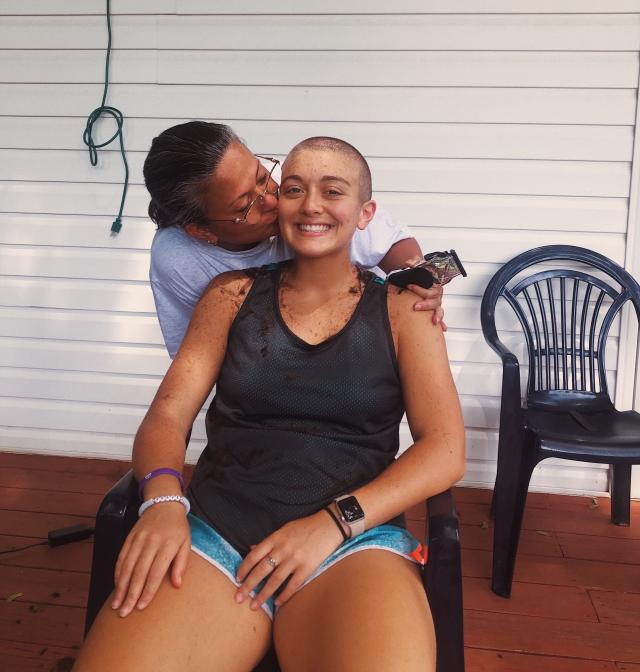 Rachael Johnson gets a kiss on the cheek from her mother as her head is shaved.