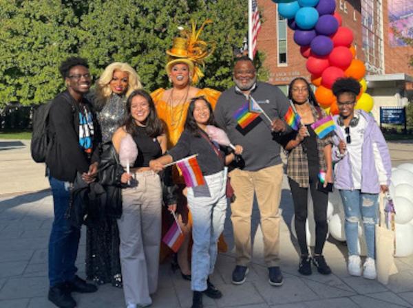 Kean President Lamont Repollet poses with students under a multicolored balloon rainbow.