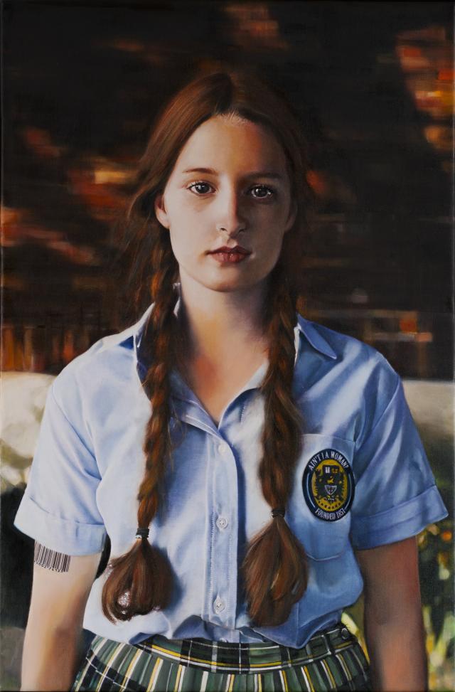 A painting of a white woman, with long, brown pigtail braids, wearing a blue, button-up t-shirt tucked into her plaid skirt that is green, yellow, white, and black. On her shirt is a patch sewn on the pocket that says, “Ain’t I A Woman?” and she has a tattoo on her right arm with a barcode. The background behind her is blurry. 