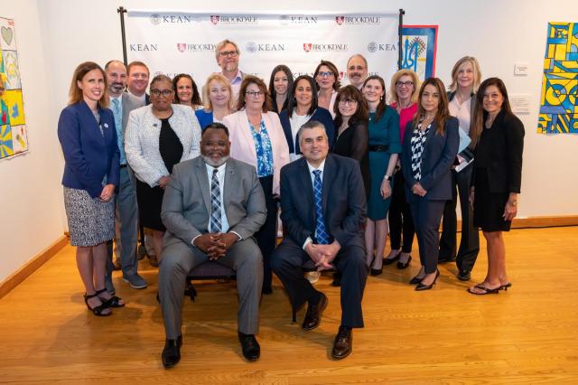 Presidents Reppollet and Stout sit. Behind them is a group of senior adminstrators from Kean University and Brookdale Community College.