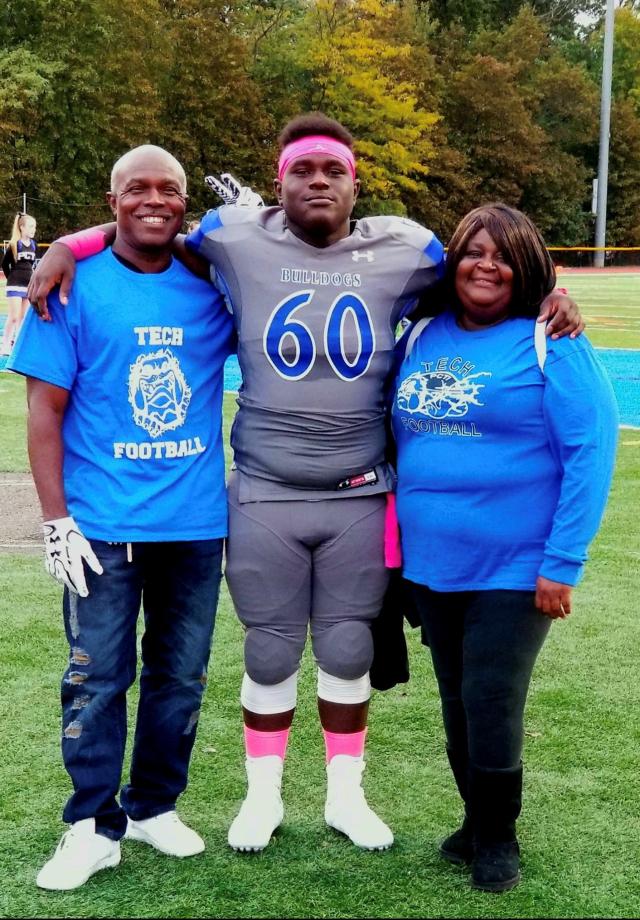 Tymere in his high school football uniform, with both of his parents