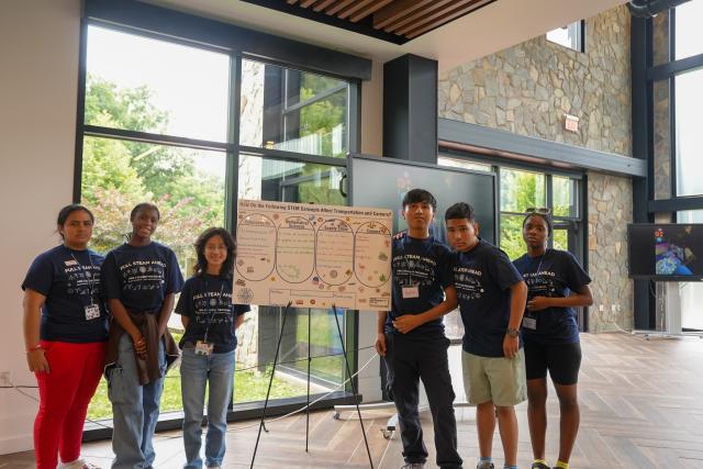 Pre-college students display a poster of things they learned at a summer STEM program