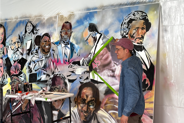 Kean alumnus, artist Ricardo Roig, stands in front of his human rights-inspired mural