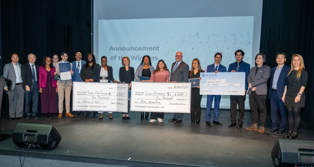 The competitors and judges at the Business Plan Competition pose on stage.