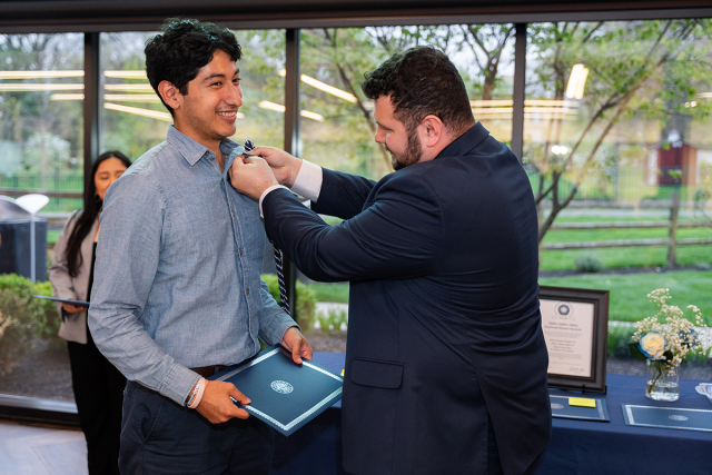 A student receives his Tri-Alpha pin.