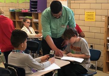 A teacher is helping a student with work in the classroom. 