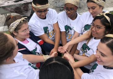A group of students holding hands together in a circle. 