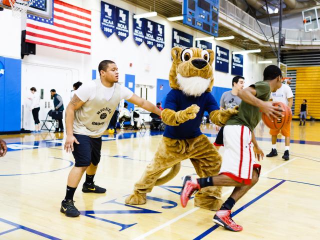 Kean University Cougar playing basketball with students