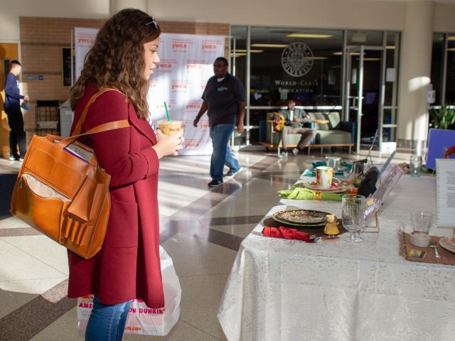 Kean student stands, looking at the Empty Place At The Table Art Display