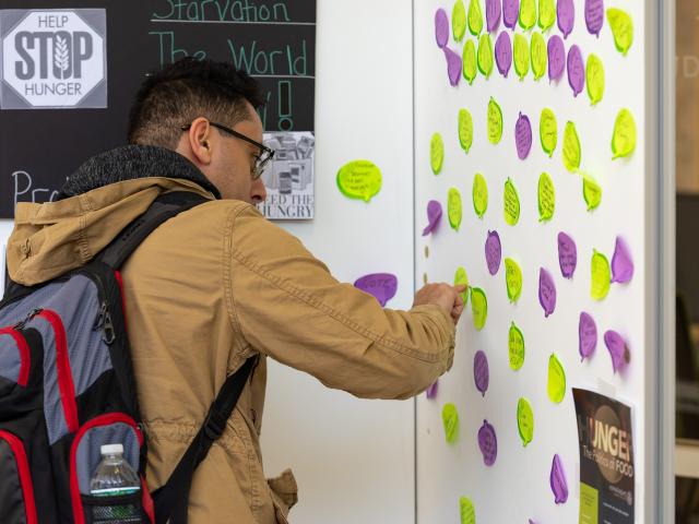 A Kean University student writes on the "Hunger Wall," which encourages students to think about hunger in the U.S.