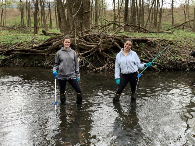 Two students pose in the Elizabeth River during their river clean up. 