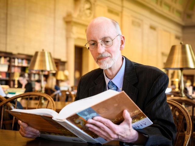 Dr. Jeff Toney sits reading a book at the MIT library