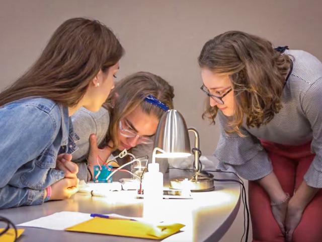 Three students collaborate on a renewable energy experiment.