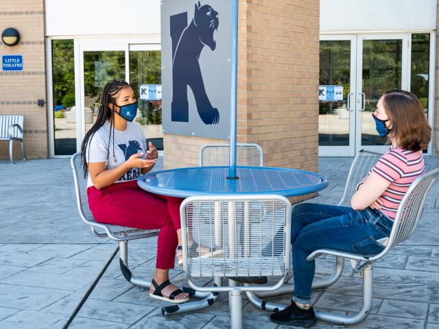 Two students chat on the Miron Student Center patio
