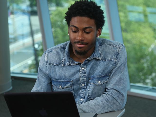 A Kean University student works on a laptop.