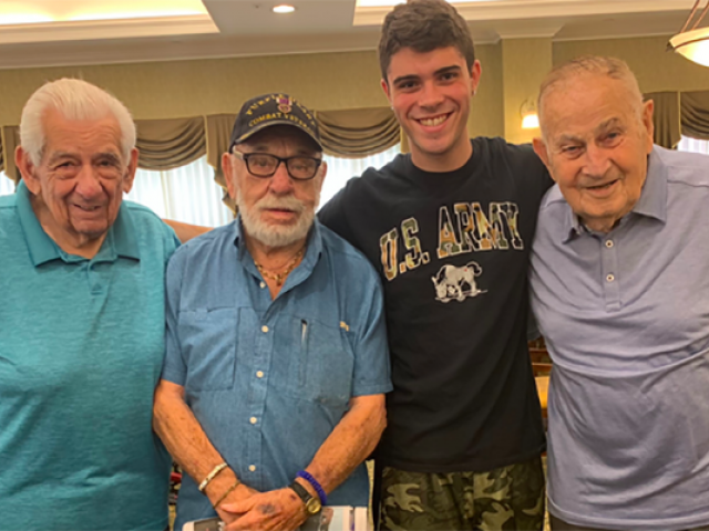 Kean student, Michael Naya, smiles for a photo with 3 World War 2 veterans.