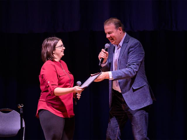 A young woman accepting an award from Art Director, John Wooten on the right