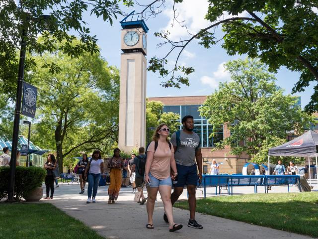 Students walk on Kean's campus in Union, with the clock tower behind them.