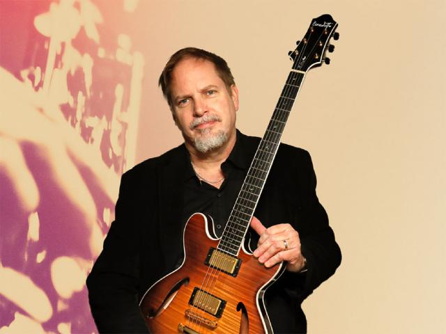 Male in his 60s holding a guitar