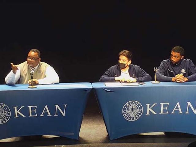 Kean President Repollet, Student Org President Pleitez and Student Trustee Robinson sit at two tables on a stage.