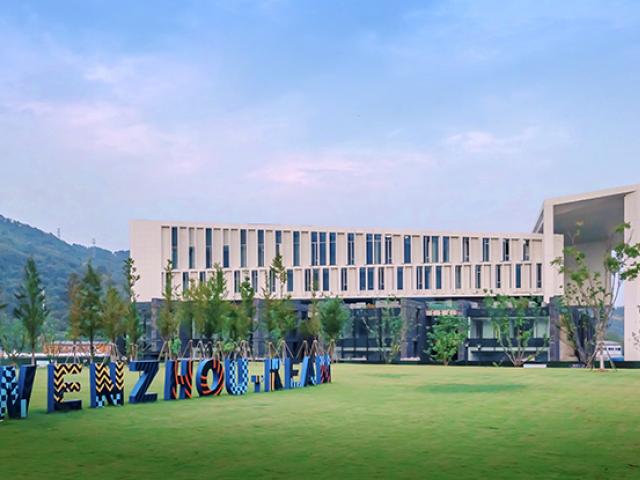 Wenzhou-Kean University's architecture building, with blue sky and Wenzhou-Kean in large letters on the lawn.