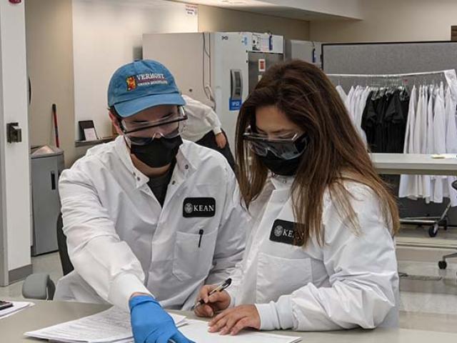 Two workers at Kean's COVID-19 lab collaborate as they review paperwork.