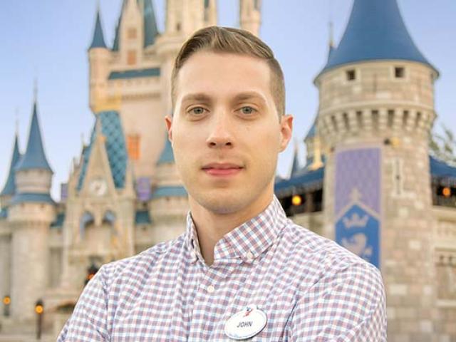John Weigele standing with his arms folded in front of the Magic Kingdom at Disney World.