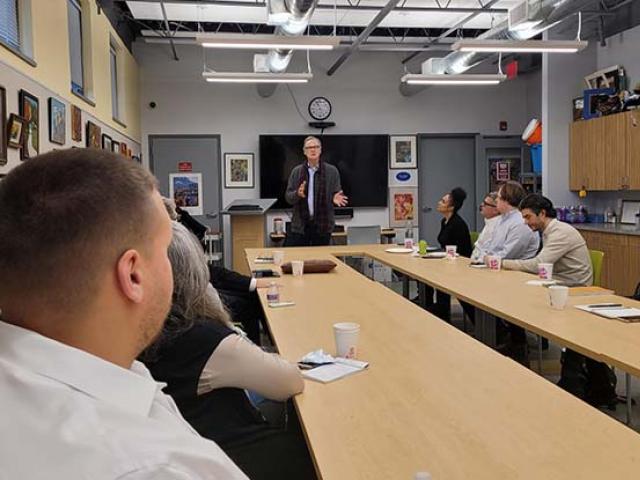 Michael Graves College Dean David Mohney stands at the head of a long table, gesturing.