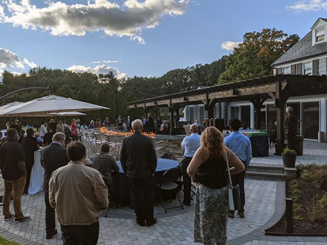 A large group of people walking on a gray stone patio.