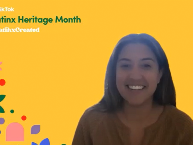 A young hispanic woman smiles. Latinx Heritage Month is displayed.