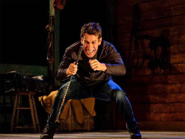 A jockey with a horse whip and squatting on the stage