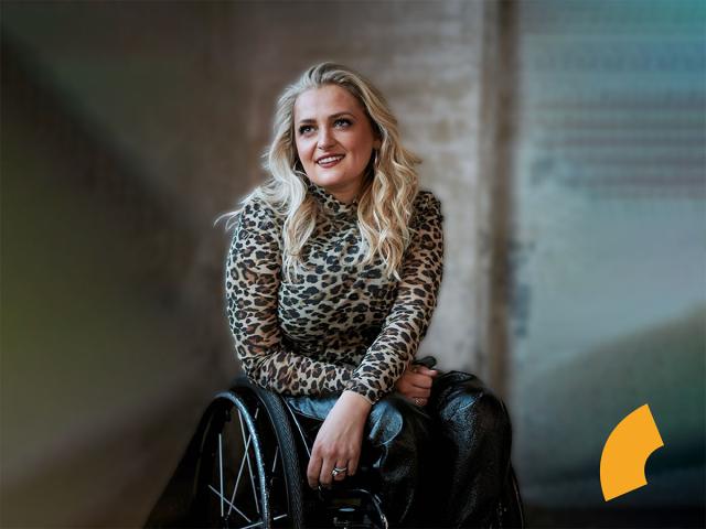 Blond, curly hair woman with a leopard shirt, sitting on a wheelchair