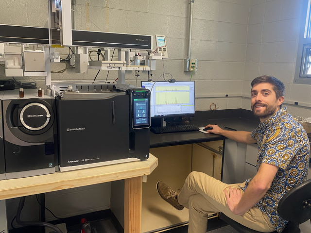 Scott LaFontaine sits before a laptop computer and sophisticated scientific equipment