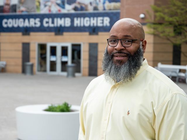 Former NY Giant Kareem McKenzie in front of Cougars Climb Higher sign on campus