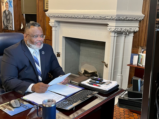 Kean President Repollet at his desk before a large computer monitor testifying at a Congressional briefing