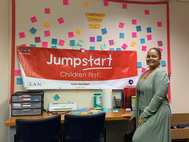 Kean alumna Yoleiny Grullon stands at the Jumpstart office bulletin board