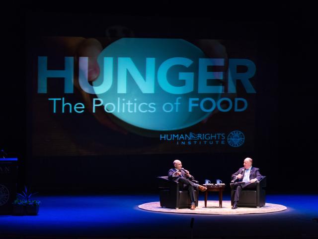 Two men discuss Hunger, The Politics of Food in a conference