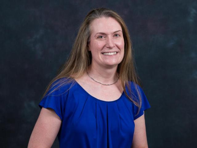 Laura Lorentzen, with long light-brown hair in a blue blouse, smiles.