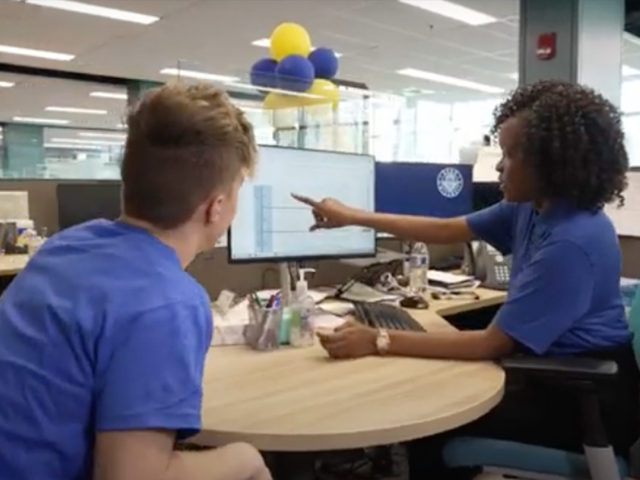 A Kean advisor points to a video screen as a student looks on.