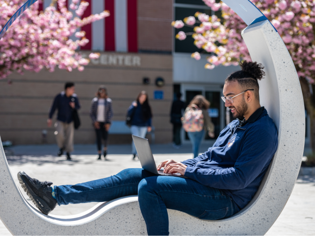 Student working on his laptop while seated on outdoor sculptural furniture