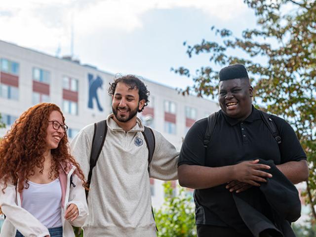 Three smiling people walking together on Kean campus