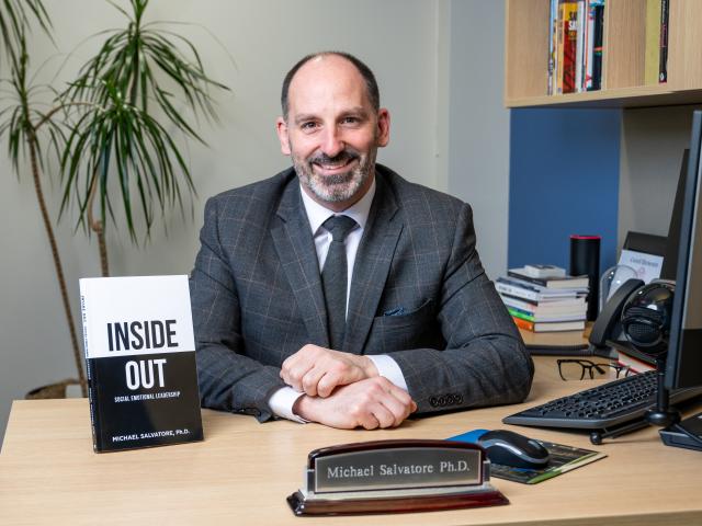 Mike Salvatore in a posed shot at his desk, showing his new book, Inside Out