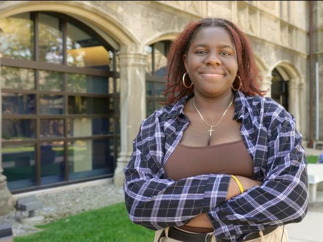 Oluwatunmise Alabi stands outside Kean Hall, grinning with her arms crossed.